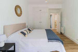 1 dormitorio blanco con 1 cama grande y espejo en Piso de diseño en el Sardinero, en Santander