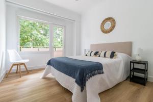een witte slaapkamer met een bed en een raam bij Piso de diseño en el Sardinero in Santander