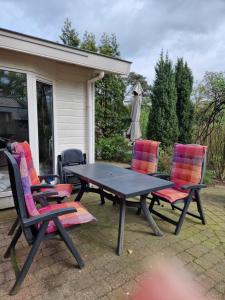 - une table de pique-nique et 4 chaises sur la terrasse dans l'établissement Bospark Ede Huisje 31, à Ede