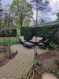 een tuinhuisje met stoelen en een bank in een tuin bij Bospark Ede Huisje 31 in Ede