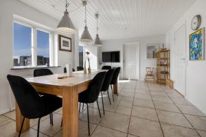 a dining room with a wooden table and black chairs at Pool house with beautiful view by the sea - SJ650 in Lemvig