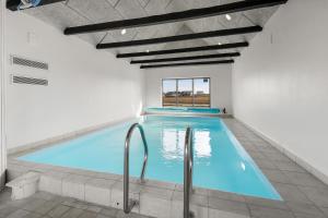 a large indoor swimming pool with blue water at Pool house with beautiful view by the sea - SJ650 in Lemvig