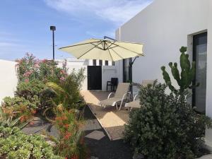 un patio con ombrellone, sedie e piante di Las Buganvillas 77 a Playa Blanca