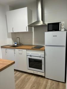 リバデセリャにあるApartamento Arenaのキッチン(白いキャビネット、コンロ、冷蔵庫付) +8枚の写真