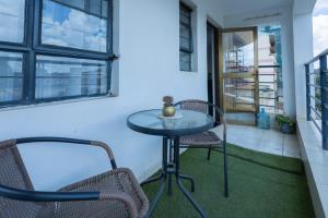Furnished 1 Bedroom Apartment in Nairobi. 15 Mins to CBD. Free WI-FI & Parking في نيروبي: طاولة صغيرة و كرسيين على شرفة