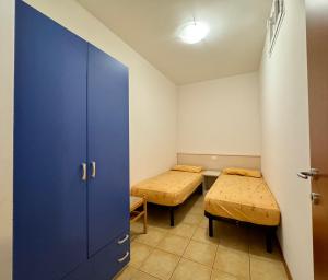ビビオーネにあるCondominio Bussolaのベッド2台と青いドアが備わる小さな部屋です。