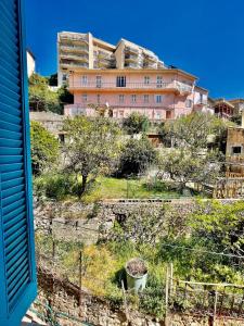 ein rosafarbenes Gebäude auf einem Hügel mit Bäumen in der Unterkunft Charming T2 - 2 Minutes Walk From Monaco in Beausoleil