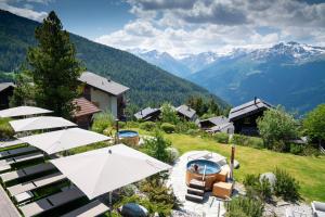 un complexe avec des parasols et une vue sur les montagnes dans l'établissement Chandolin Boutique Hotel, à Chandolin