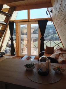 salon z dużym oknem i stołem z jedzeniem w obiekcie Vikendica "Koliba kraj puta" w mieście Divčibare