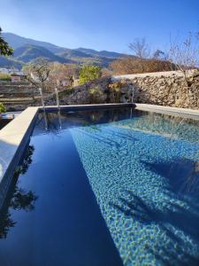 una piscina de agua azul y montañas de fondo en Cal Gat en Les Planes d'Hostoles