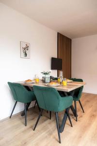 una mesa de comedor con sillas verdes en una habitación en Kassel Rooms en Kassel
