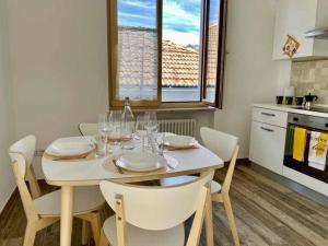 a dining room table with white chairs and a kitchen at Casa del Tempo Irma Tassullo Ospitar in Tassullo