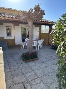 a patio with a table and chairs and a tree at HOLIDAYLAND 433 VILLA T2 MEZZANINE 6 couchages NARBONNE PLAGE in Narbonne-Plage