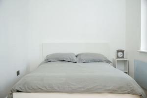een witte slaapkamer met een groot bed met 2 kussens bij Crystal apartments in Croydon
