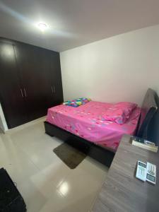 ein kleines Schlafzimmer mit einem rosa Bett und einem Tisch in der Unterkunft Don carmelo in Valledupar