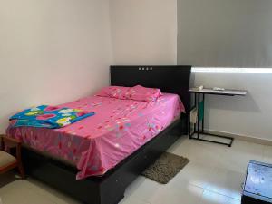 1 dormitorio con cama rosa y mesa en Don carmelo, en Valledupar