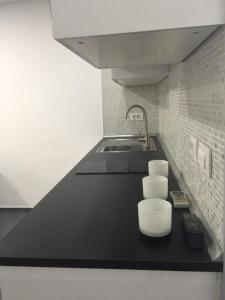 a kitchen with a black counter and a sink at Wonderful stay in Tenerife Royal Gardens Resort! in Playa de las Americas