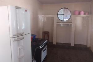 a kitchen with a stove and a white refrigerator at Casa espaçosa, piscina, churrasqueira , area festa in Corumbá