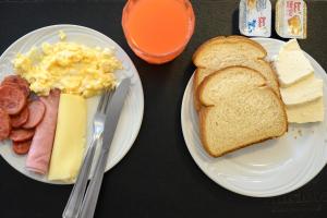 two plates of breakfast food with eggs sausage and bread at Colonial Flat Hotel in Itapetininga