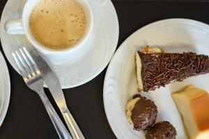 a plate with a piece of cake and a cup of coffee at Colonial Flat Hotel in Itapetininga