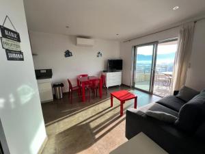 a living room with a couch and a red table at Appartement Sole - vue golfe de Porto Vecchio in Porto-Vecchio