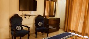 a bedroom with two chairs and a dresser with a television at Gold Suite 402 Bhurban in Murree