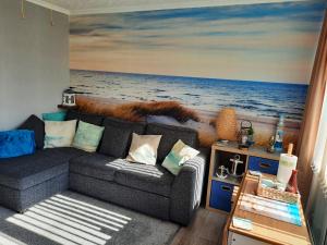 a living room with a couch and a painting of the ocean at Family Tides-Chapel Saint Leonards in Chapel Saint Leonards