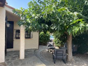 a group of chairs sitting under a tree at Maison proche de la mer in Sainte-Marie-la-Mer