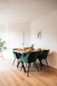 カッセルにあるKassel Rooms Iのテーブルと緑の椅子のあるダイニングルーム