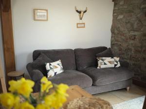 un canapé gris dans un salon avec des fleurs jaunes dans l'établissement Noxon Pond Cottage, à Clearwell