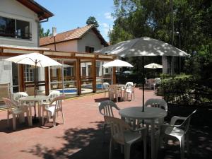 un patio con mesas, sillas y sombrillas en Posada La Campiña en Valle Hermoso