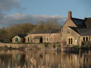 an old brick house next to a body of water at Noxon Pond Cottage in Clearwell