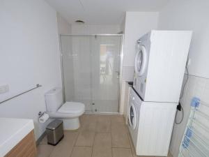a white bathroom with a toilet and a refrigerator at Luxury Suite On Flinders Street in Melbourne