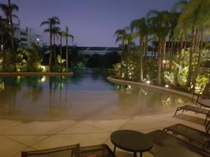 uma piscina de água com palmeiras e uma mesa em Resort, Espaço Verde e Lazer - Centro - São Paulo em São Paulo