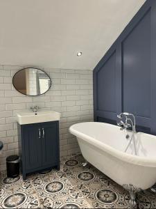 La salle de bains est pourvue d'une grande baignoire blanche et d'un lavabo. dans l'établissement The Alma Inn, à Sowerby Bridge