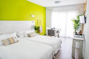 two beds in a room with a green wall at Dunas Club - Hotel & Apartamentos in Corralejo