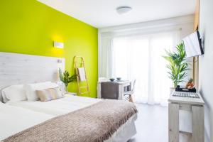 a bedroom with a white bed and a green wall at Dunas Club - Hotel & Apartamentos in Corralejo