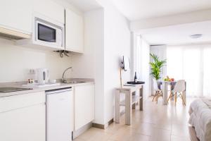 a white kitchen with white cabinets and a table at Dunas Club - Hotel & Apartamentos in Corralejo