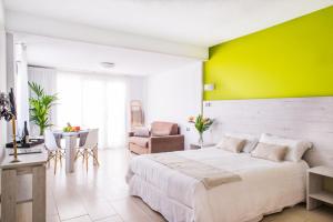a bedroom with a white bed and a yellow wall at Dunas Club - Hotel & Apartamentos in Corralejo