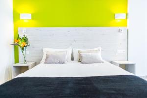 a bedroom with a large white bed with a yellow wall at Dunas Club - Hotel & Apartamentos in Corralejo