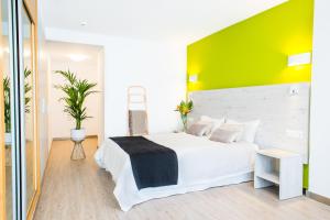 a bedroom with a white bed and a green wall at Dunas Club - Hotel & Apartamentos in Corralejo