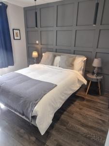a bedroom with a large bed with a gray headboard at Richmond Apartments in London