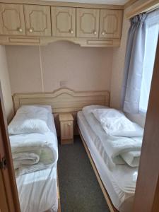 two twin beds in a small room with cabinets at Thornbury Holiday Park in Thornbury
