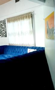 ein blaues Sofa in einem Zimmer mit Fenster in der Unterkunft Monalissa One bedroom apartment in Kisumu