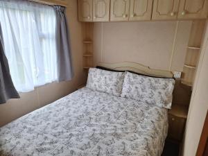 een bed in een kleine kamer met een raam bij Thornbury Holiday Park in Thornbury