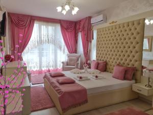 Dormitorio rosa con cama grande y cortinas rosas en Вила с минимален басейн и джакузи, en Bankya