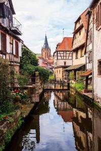 une rivière dans une ville avec des bâtiments et une église dans l'établissement Appartements « La Parenthèse », à Wissembourg