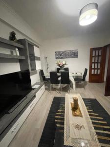 a living room with a large television and a table at Quarto Suite Relaxante in Almada