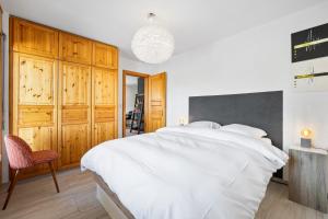 una camera con un grande letto bianco e armadi in legno di Ambassador II nr 10 - 4 pers - pres des pistes a Nendaz