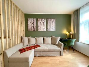 a living room with a couch and a green wall at Parkside City Apartment - Leipzig Zentrum - Netflix in Leipzig